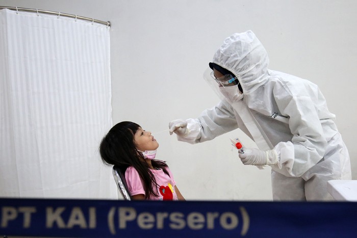 Petugas kesehatan melakukan tes swab PCR pada seorang anak di Stasiun Pasar Senen, Jakarta, Kamis (23/12/2021).