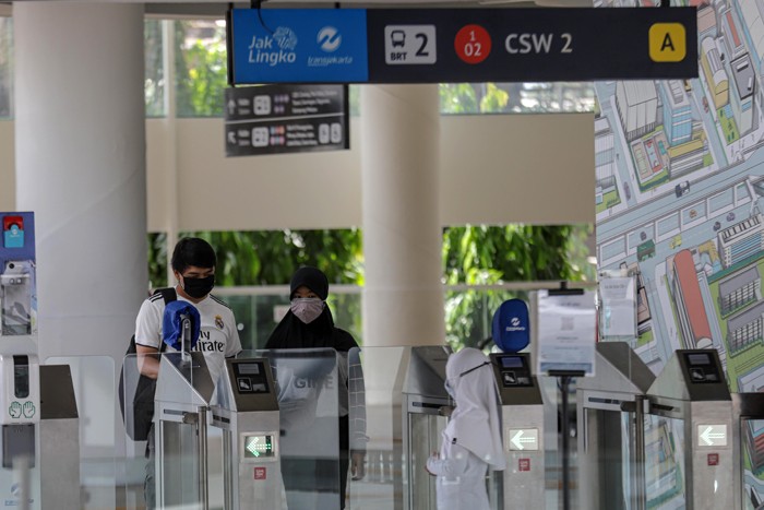 Warga memindai kode batang menggunakan aplikasi PeduliLindungi sebelum memasuki Halte Integrasi Centrale Stichting Wederopbouw (CSW).