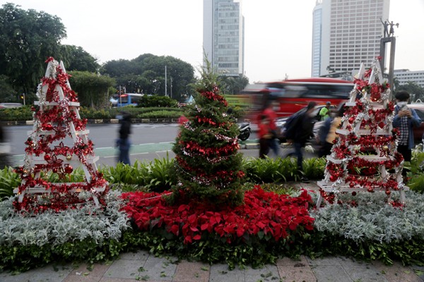 Seorang wanita menghias pohon Natal di kawasan Bundaran HI, Jakarta, Kamis (23/12/2021).