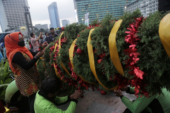 Seorang wanita menghias pohon Natal di kawasan Bundaran HI, Jakarta, Kamis (23/12/2021).
