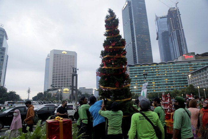Seorang wanita menghias pohon Natal di kawasan Bundaran HI, Jakarta, Kamis (23/12/2021).