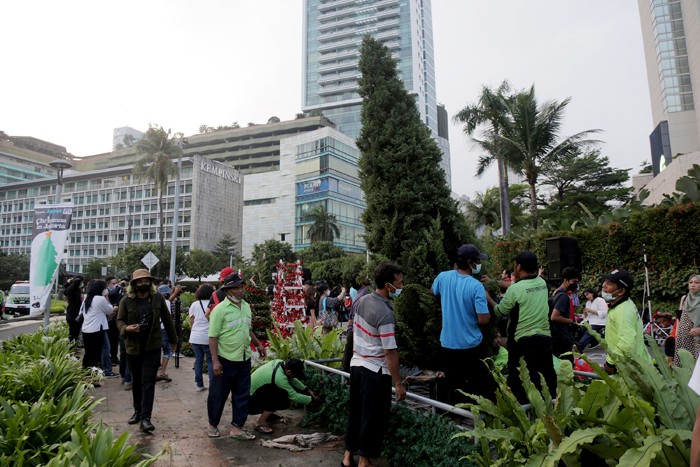 Seorang wanita menghias pohon Natal di kawasan Bundaran HI, Jakarta, Kamis (23/12/2021).