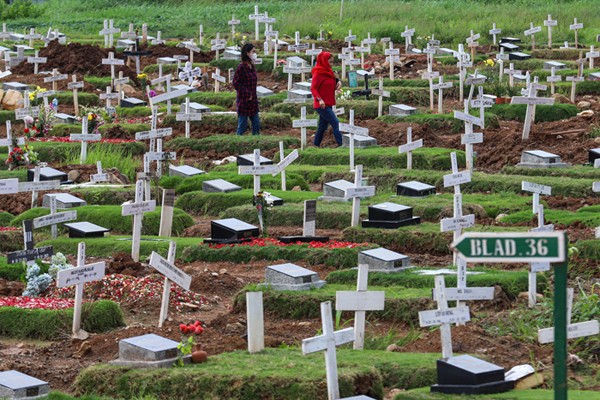 Warga menabur bunga di atas makam keluarganya saat ziarah di Tempat Pemakaman Khusus Covid-19, Rorotan, Jakarta Utara, Sabtu (25/12/2021).
