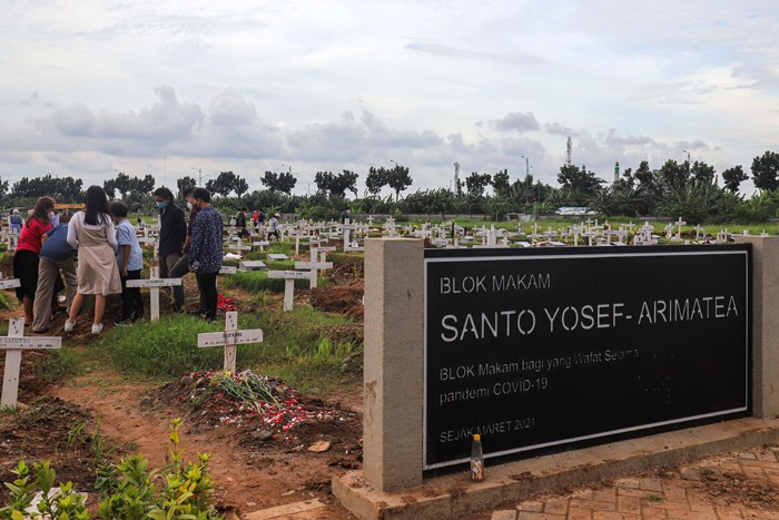 Warga menabur bunga di atas makam keluarganya saat ziarah di Tempat Pemakaman Khusus Covid-19, Rorotan, Jakarta Utara, Sabtu (25/12/2021).