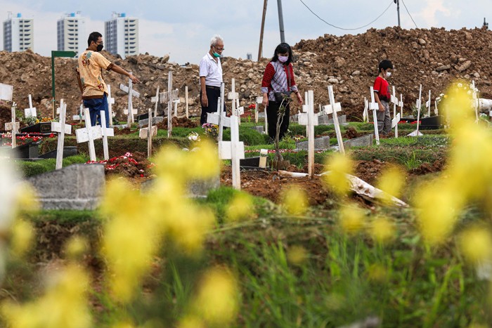 Warga menabur bunga di atas makam keluarganya saat ziarah di Tempat Pemakaman Khusus Covid-19, Rorotan, Jakarta Utara, Sabtu (25/12/2021).