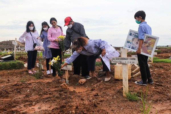 Warga menabur bunga di atas makam keluarganya saat ziarah di Tempat Pemakaman Khusus Covid-19, Rorotan, Jakarta Utara, Sabtu (25/12/2021).