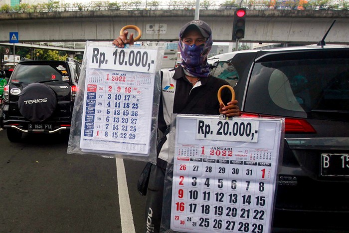 Pedagang musiman menawarkan kalender 2022 kepada pengendara di lampu merah kawasan, Jakarta Pusat, Selasa (28/12/2021).