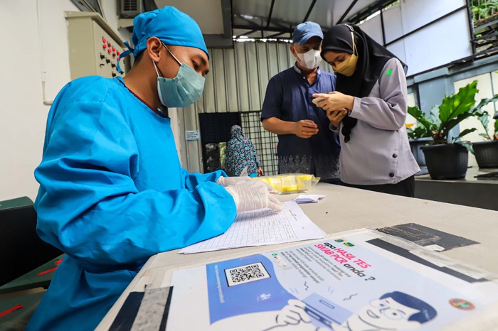 Petugas kesehatan melakukan tes usap (swab test) PCR kepada warga di Puskesmas Kecamatan Mampang Prapatan, Jakarta Selatan, Selasa (28/12/2021).