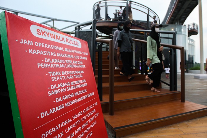 Pengunjung berswafoto dengan latar belakang lansekap perkotaan di Skywalk, Senayan Park, Jakarta, Rabu (29/12/2021).