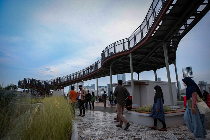 Pengunjung berswafoto dengan latar belakang lansekap perkotaan di Skywalk, Senayan Park, Jakarta, Rabu (29/12/2021).
