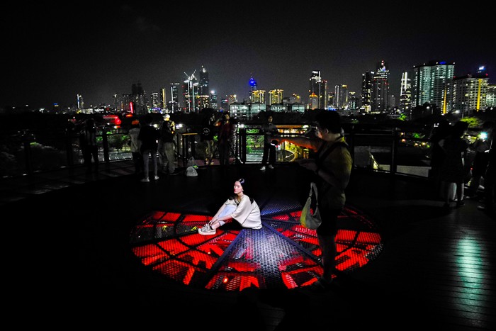Pengunjung melihat deretan gedung bertingkat dari Skywalk Senayan Park, di Jakarta, Rabu (29/12/2021).