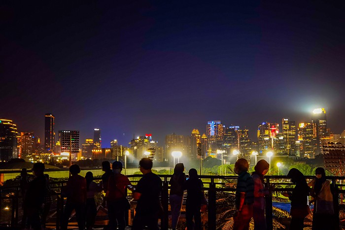 Pengunjung melihat deretan gedung bertingkat dari Skywalk Senayan Park, di Jakarta, Rabu (29/12/2021).