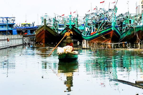 Warga menggunakan perahu kecil mencari barang-barang yang dapat dijual di Muara Angke, Jakarta Utara, Senin (3/1/2022).