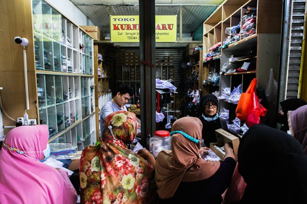 Penjual seragam sekolah saat melayani pembeli di Pasar Embrio, Kampung Makasar, Jakarta Timur, Minggu (2/1/2022).