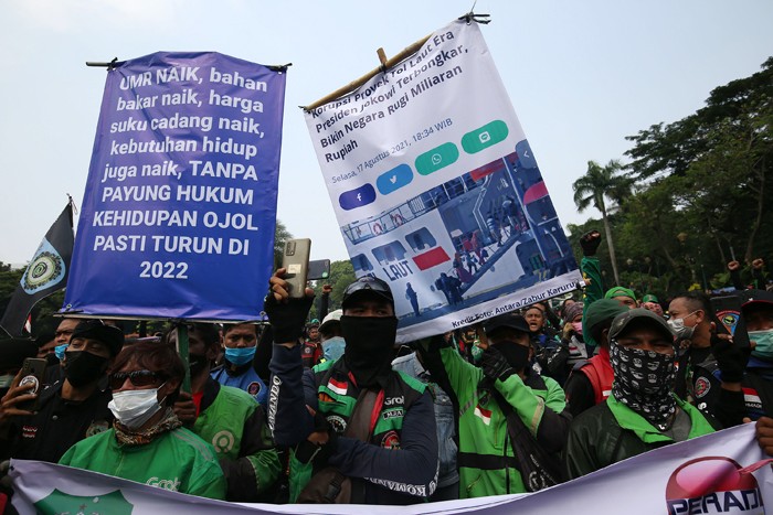 Sejumlah pengemudi ojek online membentangkan spanduk saat aksi unjuk rasa di Jakarta, Rabu (5/1/2022).