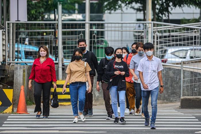 Pekerja melintasi jalur pedestrian di kawasan Sudirman saat jam pulang kerja di Jakarta, Rabu (5/1/2022).