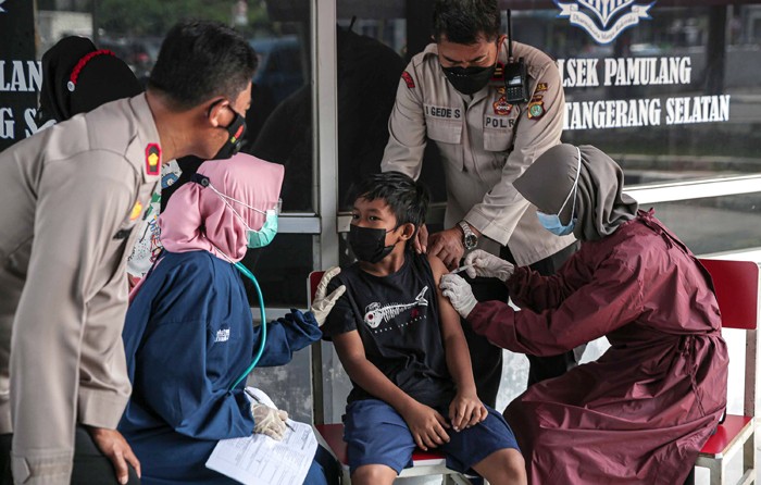 Tenaga kesehatan menyuntikan vaksin Covid-19 ke seorang anak dibawah kolong Jalan Layang Gaplek, Pamulang, Tangerang Selatan, Banten, Kamis (6/1/2022).