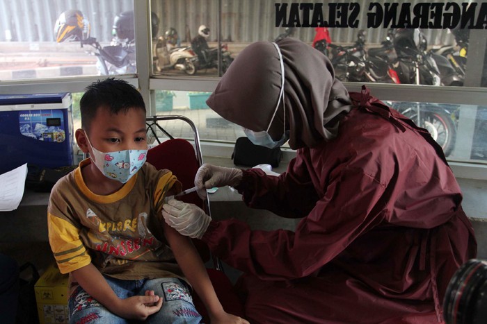 Tenaga kesehatan menyuntikan vaksin Covid-19 ke seorang anak dibawah kolong Jalan Layang Gaplek, Pamulang, Tangerang Selatan, Banten, Kamis (6/1/2022).
