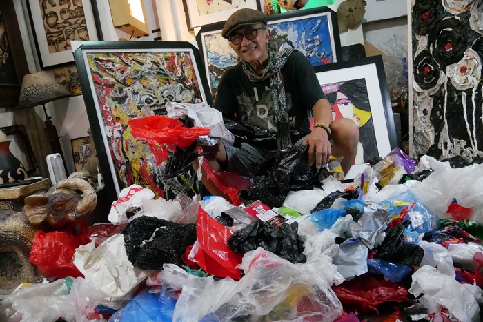 Pengrajin Dwiyono melukis dengan memanfaatkan limbah sampah plastik di sanggar kerja miliknya di Jakarta, Sabtu (8/1/2022).