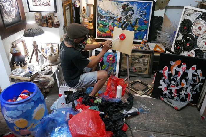 Pengrajin Dwiyono melukis dengan memanfaatkan limbah sampah plastik di sanggar kerja miliknya di Jakarta, Sabtu (8/1/2022).