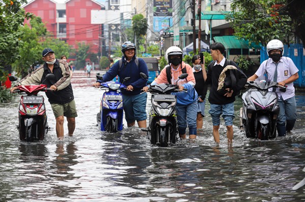 Warga mendorong sepeda motor yang mogok akibat terendam banjir di ruas Jalan Gereja Ayam, Pasar Baru, Jakarta Pusat, Selasa (18/1/2022).