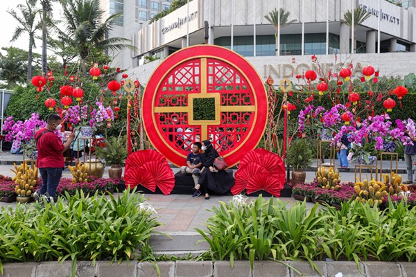 Warga berfoto dengan latar belakang ornamen bernuansa Imlek yang di pasang di kawasan Bundaran Hotel Indonesia, Jakarta Pusat, Sabtu (29/1/2022).