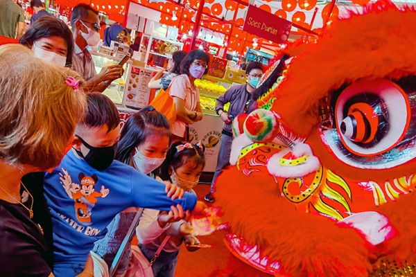 Anak-anak dan sejumlah pengunjung memberikan angpao kepada barongsai untuk menyambut perayaan Imlek di pusat perbelanjaan, Jakarta Barat, Minggu (30/1/2022).
