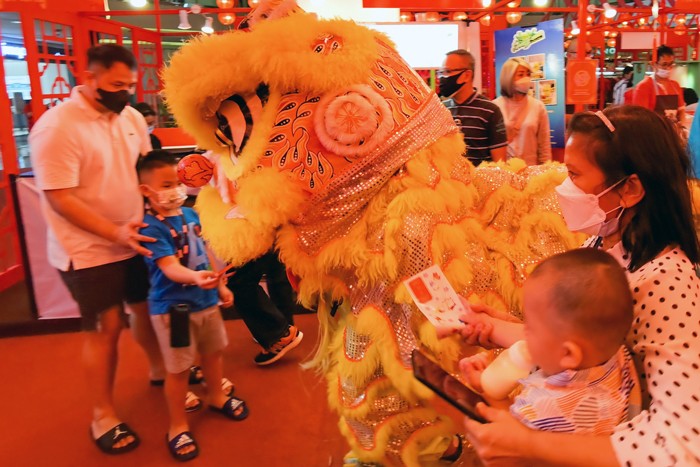 Anak-anak dan sejumlah pengunjung memberikan angpao kepada barongsai untuk menyambut perayaan Imlek di pusat perbelanjaan, Jakarta Barat, Minggu (30/1/2022).
