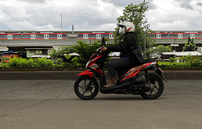 Pengendara sepeda motor melintasi kereta Light Rail Transit (LRT) Jabodebek yang diparkir di kawasan Jakasampurna, Kota Bekasi, Jawa Barat, Minggu (6/2/2022).