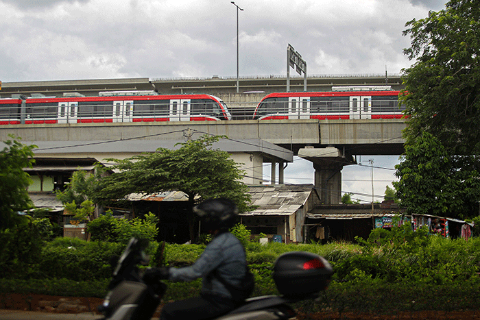 Pengendara sepeda motor melintasi kereta Light Rail Transit (LRT) Jabodebek yang diparkir di kawasan Jakasampurna, Kota Bekasi, Jawa Barat, Minggu (6/2/2022).