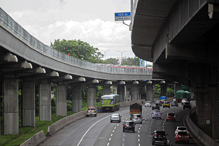 Pengendara sepeda motor melintasi kereta Light Rail Transit (LRT) Jabodebek yang diparkir di kawasan Jakasampurna, Kota Bekasi, Jawa Barat, Minggu (6/2/2022).