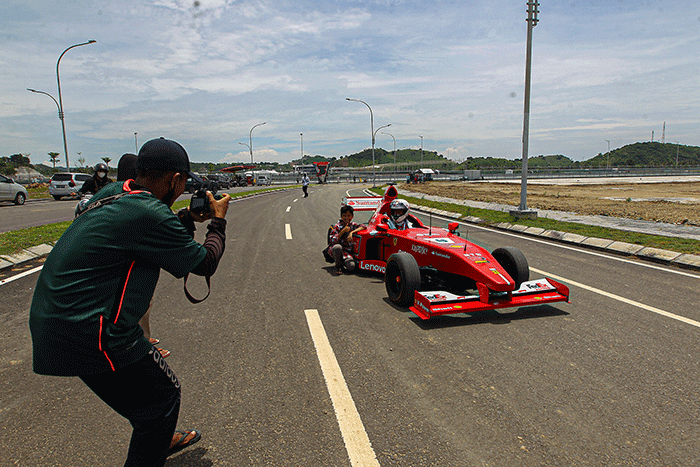 Michael Latip pembuat replika mobil balap F1 saat berpose layaknya pembalap di kawasan Sirkuit Mandalika, Lombok Tengah, NTB, Minggu (13/2/2022).