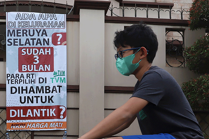Warga melintasi spanduk meminta pelantikan RT di Meruya di Perumahan Taman Villa Meruya (TMV) Meruya Selatan, Kembangan, Jakarta Barat, Sabtu (26/2/2022).