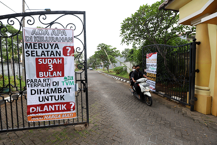 Warga melintasi spanduk meminta pelantikan RT di Meruya di Perumahan Taman Villa Meruya (TMV) Meruya Selatan, Kembangan, Jakarta Barat, Sabtu (26/2/2022).