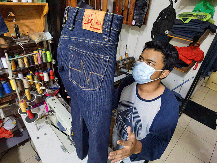 Penjual saat menyelesaikan pembuatan celana custom dan memasarkannya secara online di toko nyoel jeans, Jakarta Barat, Kamis (3/3/2022).