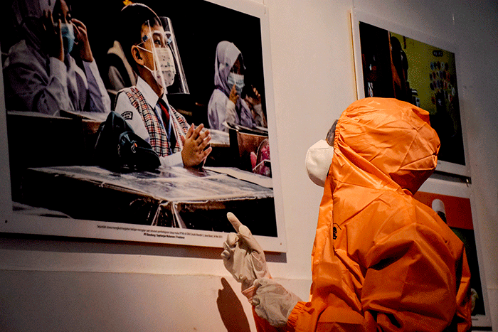 Pengunjung pameran mengenakan pakaian hazmat yang disediakan saat berkunjung ke pameran foto 731 yang diselenggarakan oleh Pewarta Foto Indonesia Bandung.