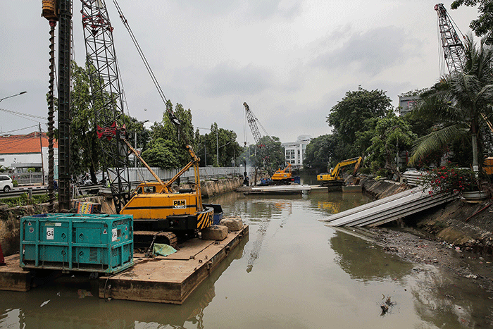 Pekerja menyelesaikan pemasangan dinding turap di kali pasar baru, Jakarta, Sabtu (12/3/2022).