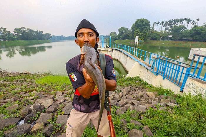 Warga saat memancing ikan dengan cara inovatif menggunakan modifikasi senapan angin di Situ Gintung, Tangerang Selatan, Kamis (17/3/2022).