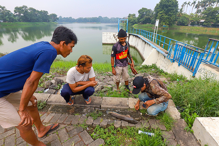 Warga saat memancing ikan dengan cara inovatif menggunakan modifikasi senapan angin di Situ Gintung, Tangerang Selatan, Kamis (17/3/2022).