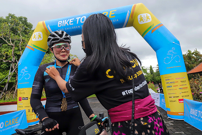 Peserta Bike To Care 2022 #BaliLoop 500 Km menunjukkan medali usai melintasi garis finish etape dua di Sol Benoa, Badung, Bali, Minggu (20/3/2022).