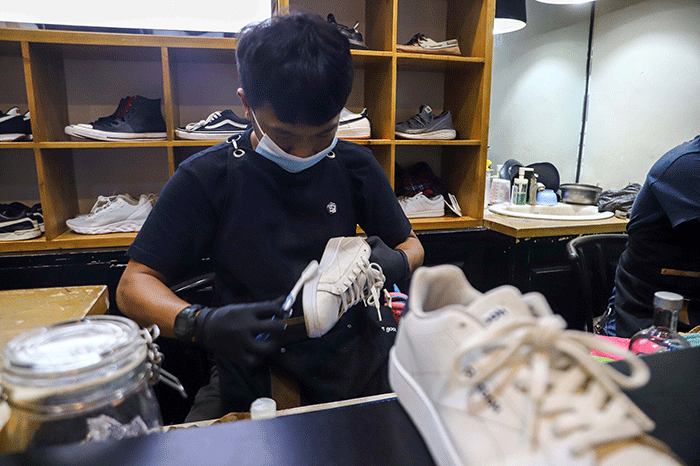 Pekerja membersihkan sepatu pelanggan di Cleaning Shoes Kicks Kemon, Haji Nawi, Jakarta Selatan, Sabtu (26/3/2022).
