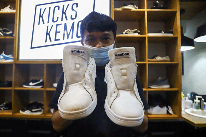 Pekerja membersihkan sepatu pelanggan di Cleaning Shoes Kicks Kemon, Haji Nawi, Jakarta Selatan, Sabtu (26/3/2022).