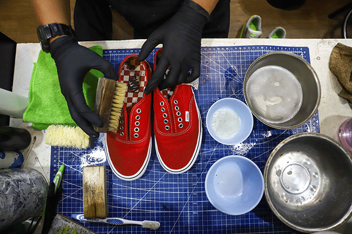 Pekerja membersihkan sepatu pelanggan di Cleaning Shoes Kicks Kemon, Haji Nawi, Jakarta Selatan, Sabtu (26/3/2022).