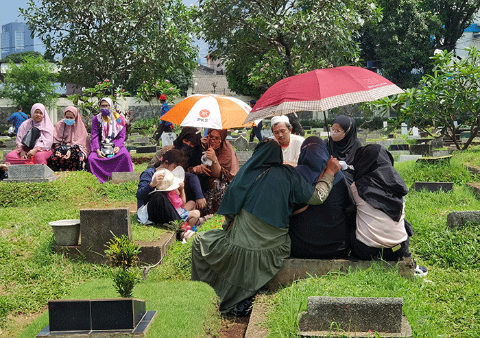 Peziarah memanjatkan doa di makam keluarga dan kerabat di Taman Pemakaman Umum (TPU) Karet Bivak, Jakarta, Minggu, (27/3/2022).