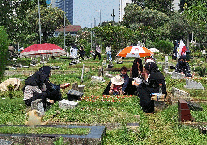 Peziarah memanjatkan doa di makam keluarga dan kerabat di Taman Pemakaman Umum (TPU) Karet Bivak, Jakarta, Minggu, (27/3/2022).