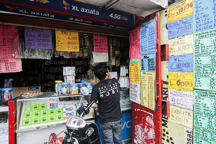 Penjual menunjukkan kartu perdana di konter pulsa kawasan Jakarta Timur, Jumat (1/4/2022).