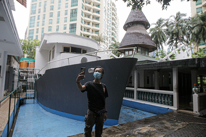 Pengunjung berswafoto berlatar belakang perahu di Masjid Al Munada Darussalam Baiturrahman, Menteng Dalam, Jakarta Selatan, Minggu (3/4/2022).