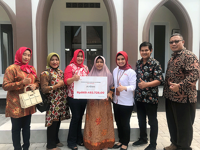 Representative Office Manager Kantor Representatif IFG Life Surabaya, Rina Tania secara simbolis menyerahkan pembayaran polis IFG Mantap kepada Ibu Munawaroh.