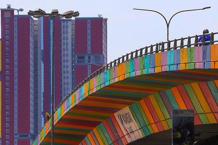 Pengendara melintas berlatar belakang gedung RSDC Wisma Atlet Kemayoran, Jakarta Pusat, Kamis (14/4/2022).
