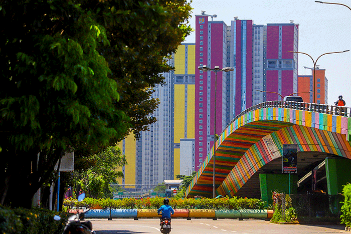 Pengendara melintas berlatar belakang gedung RSDC Wisma Atlet Kemayoran, Jakarta Pusat, Kamis (14/4/2022).
